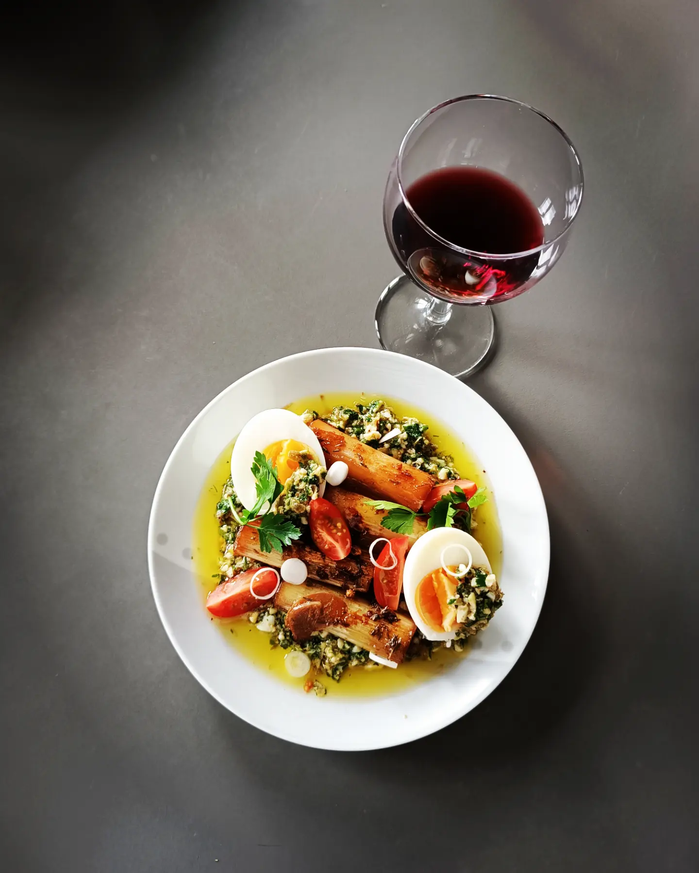 Assiette signature sur fond sombre, accompagnée d'un verre de vin